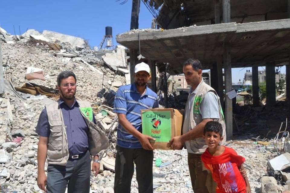 Call of Hope volunteers handing a food parcel to a family among the rubble
